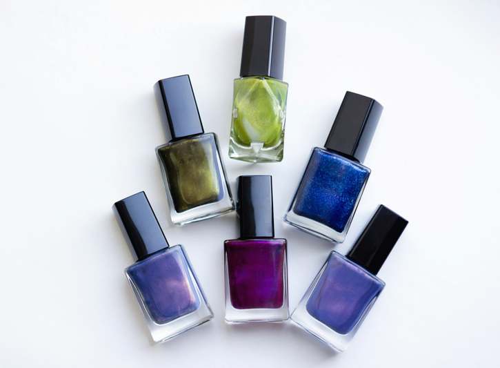 Close-up of elegant nail polish bottles with glossy finishes and metallic caps on marble surface