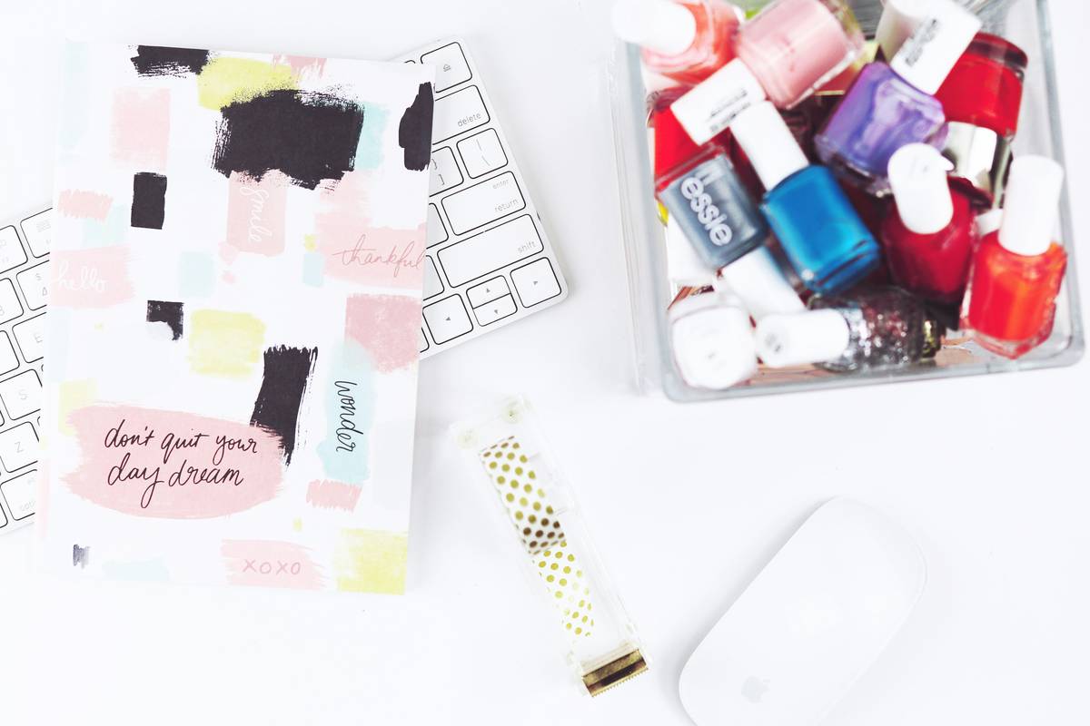 A pink acrylic manicure storage case filled with neatly arranged nail polish bottles, showing multiple rows and compartments